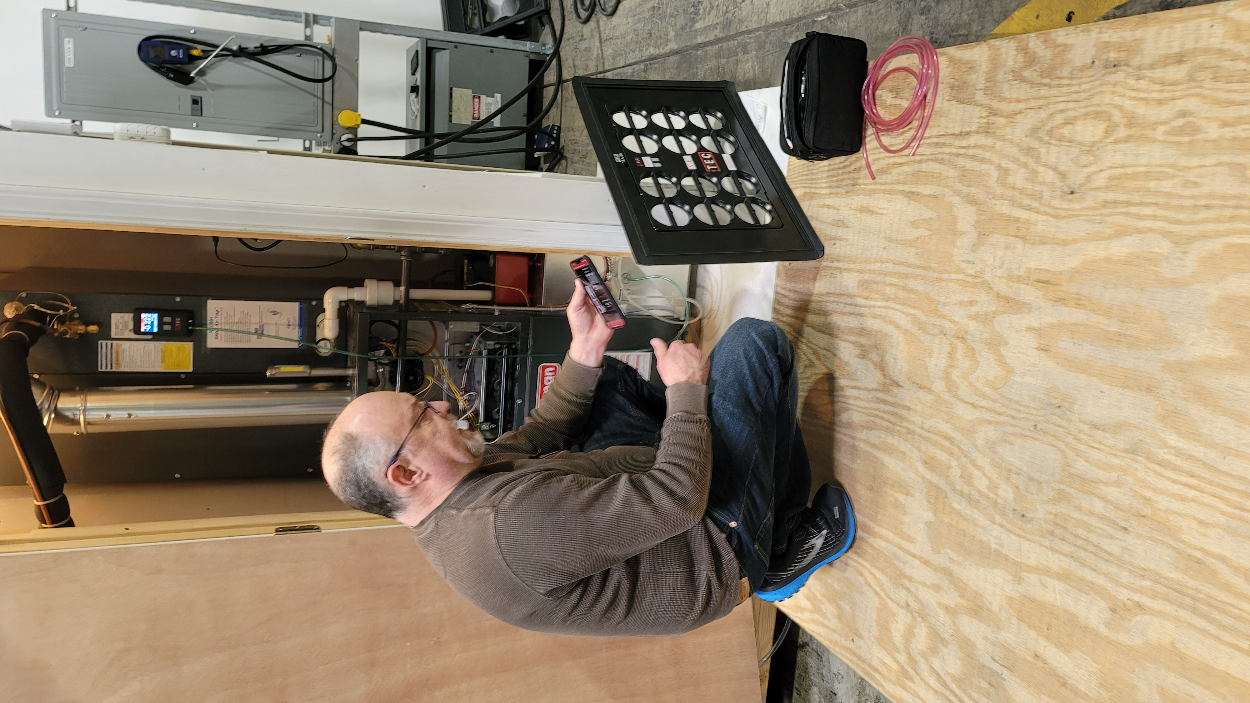 Technician holding a CPS ABM flow hood up to a ceiling supply register to measure delivered CFM