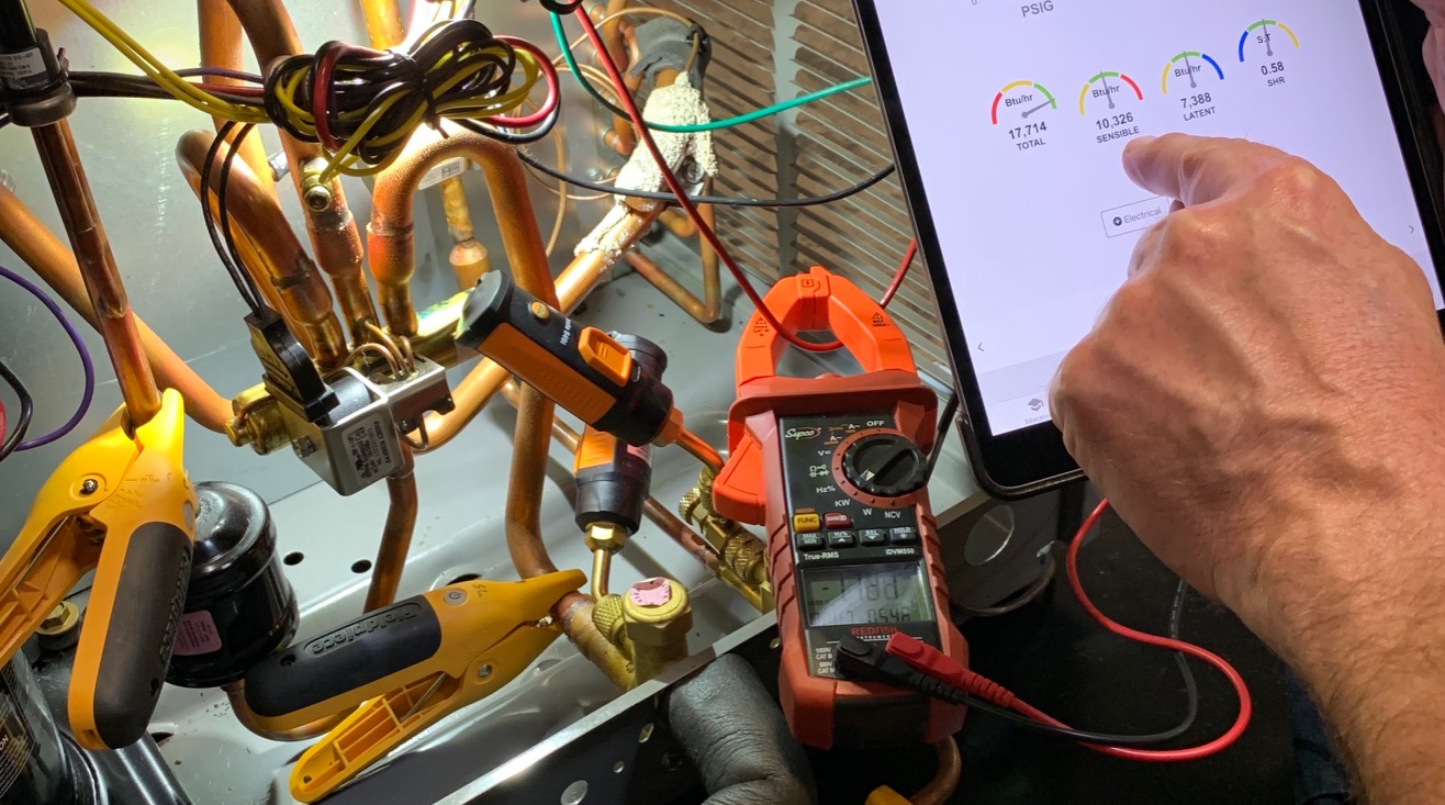 Clamp meter clamped around the compressor common wire at the contactor, with measureQuick showing live amp readings